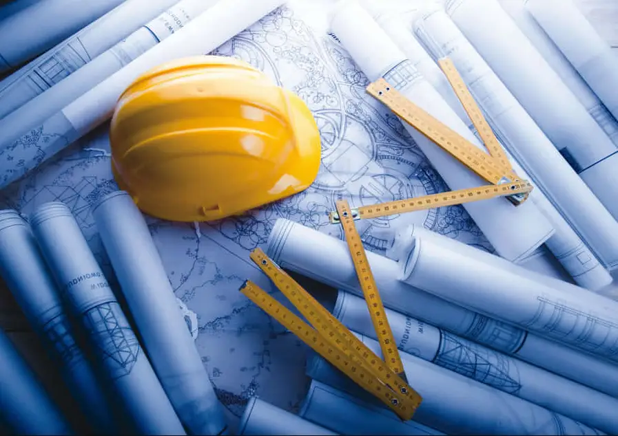 Proyecto de construcción con casco amarillo, planos técnicos desplegados y metros de madera en Barakaldo
