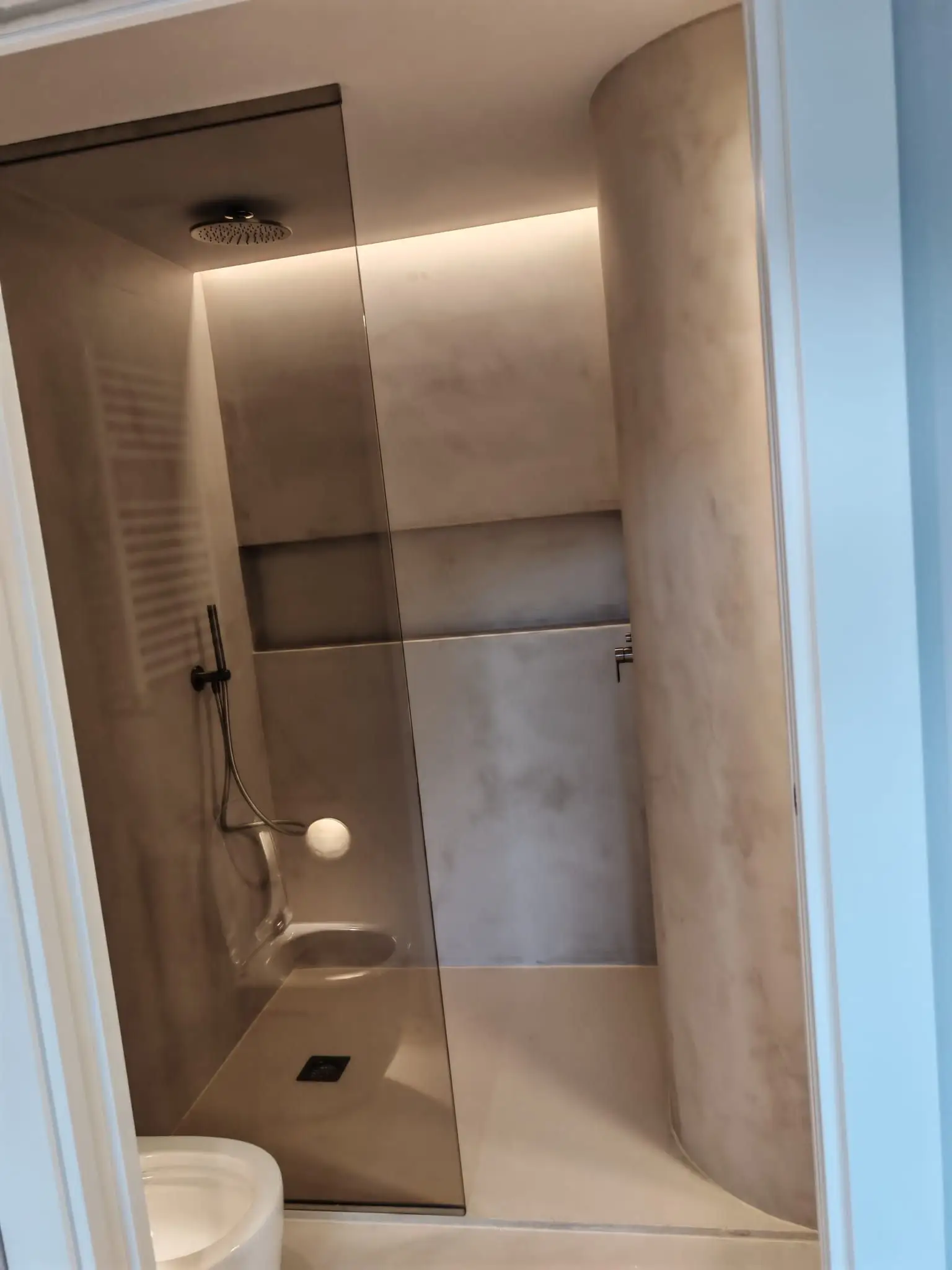 Reforma de baño con ducha de obra en microcemento gris y mampara de cristal en Barakaldo