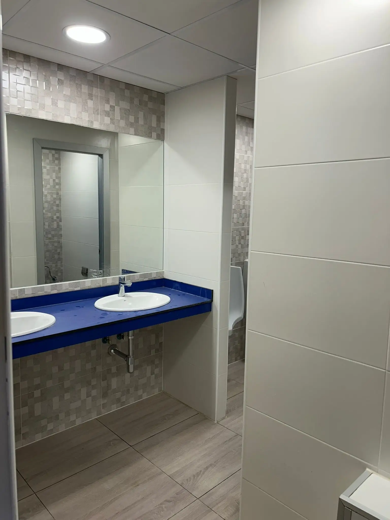 Reforma de baño con encimera azul, lavabos encastrados y revestimiento de mosaico gris en Barakaldo