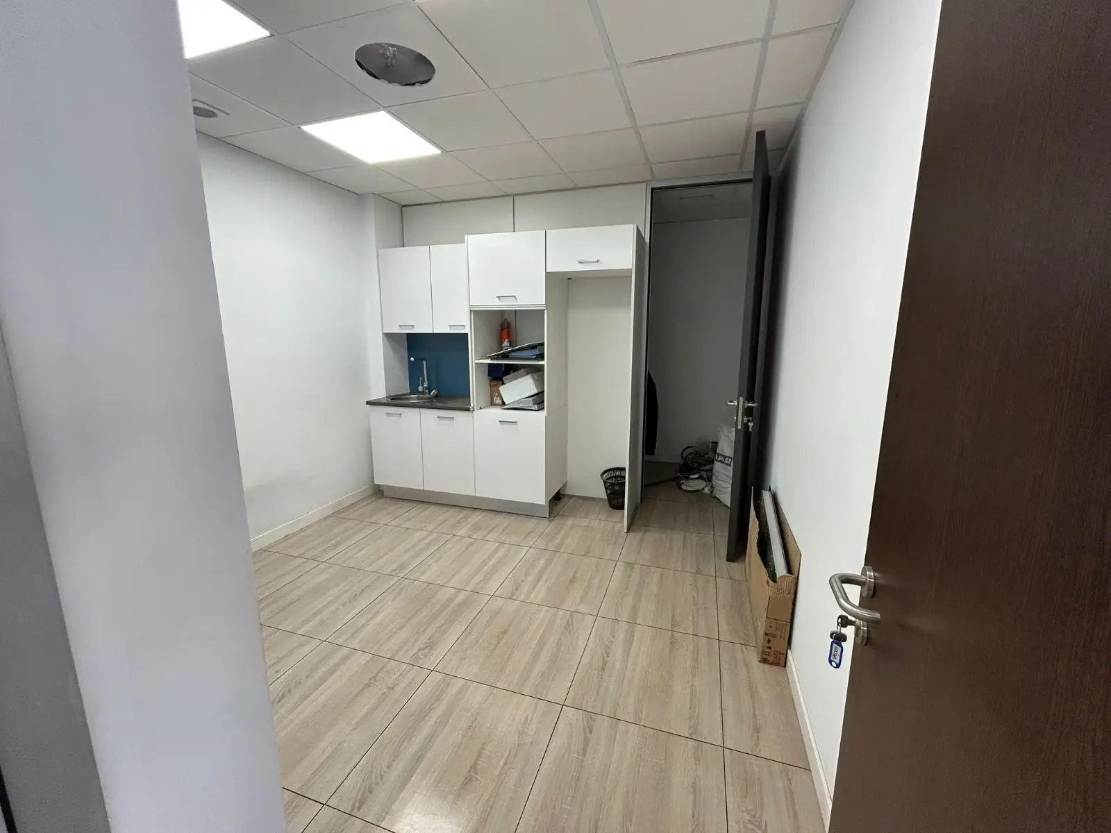 Reforma de oficina con zona de office blanca y suelo cerámico imitación madera en Barakaldo
