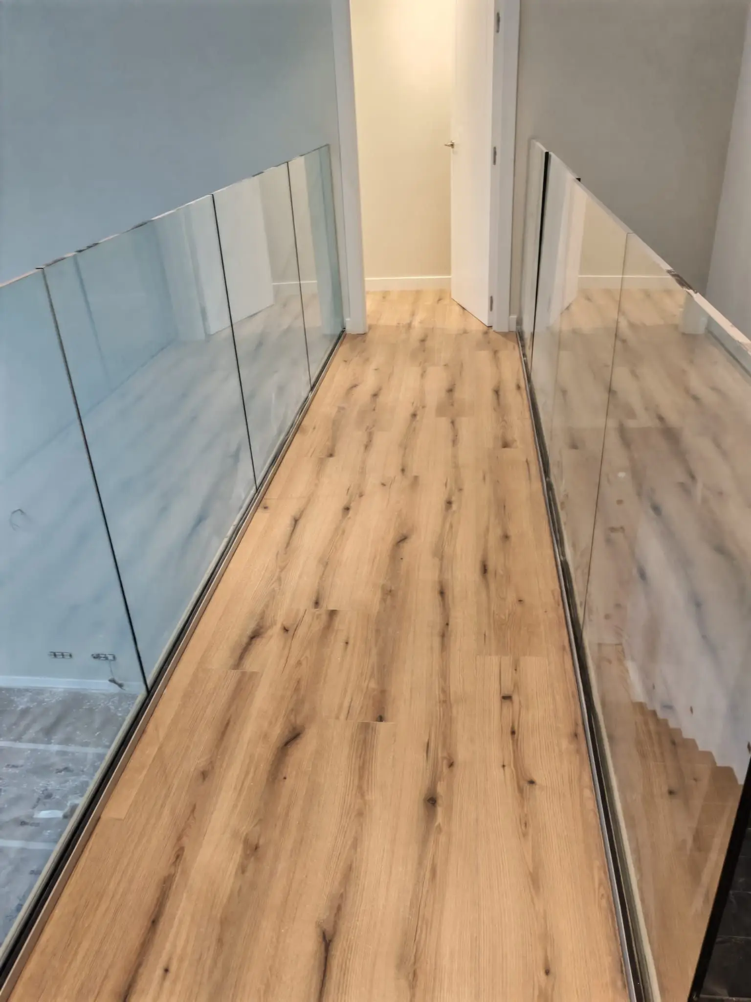 Reforma vivienda con suelo laminado de madera y barandillas de cristal minimalistas en Barakaldo